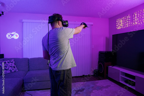 Cuadro en lienzo Man playing VR shooter game in home living room
