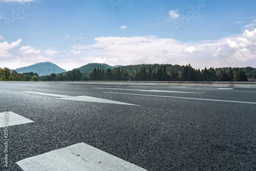 Fotografía Empty Asphalt Road Leading to Distant Green Mountains Under Blue Sky