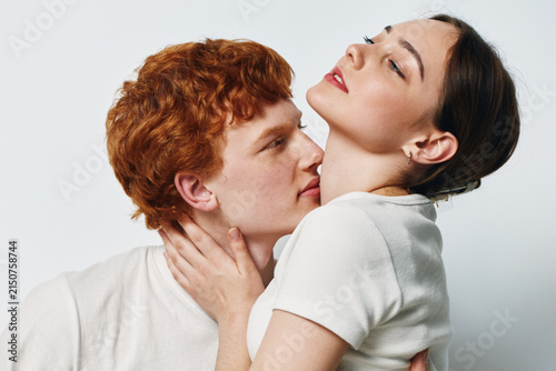 Couple, young man and woman in casual clothes embracing with affection, love and intimacy, closeup with white background, romantic and tender moment together.