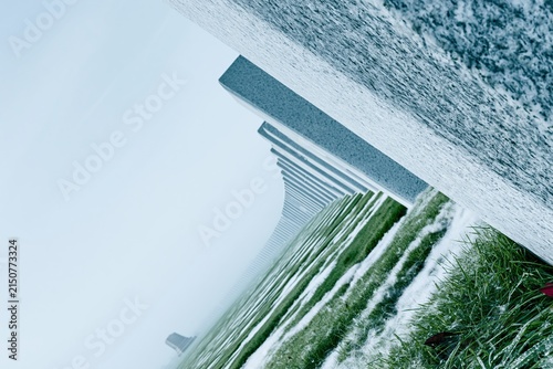 Minimalist rows of pale grey headstones recede into a misty horizon, featuring cold granite textures and damp grass for memorial tributes and remembrance