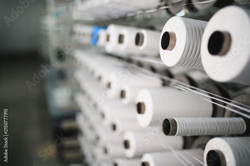 White yarn spools moving on textile production machine