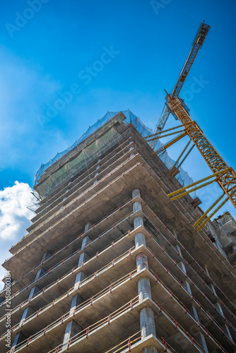 Low angle view of modern building under construction against blue sky