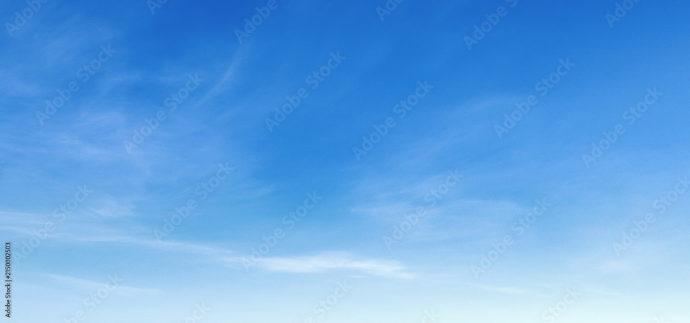 Obraz premium Soft clouds drift across a vast, serene blue sky