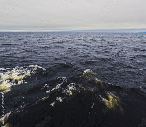 Fotografie Churning dark ocean waves under gray skies.