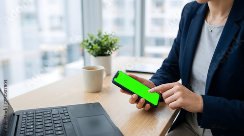 Professional Businesswoman Holding Smartphone with Green Screen for Copy Space in Modern Office Environment