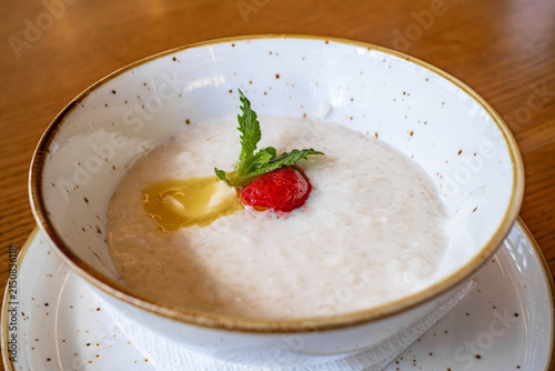 Photography rice porridge in white bowl with strawberry and mint on wooden table, early brea