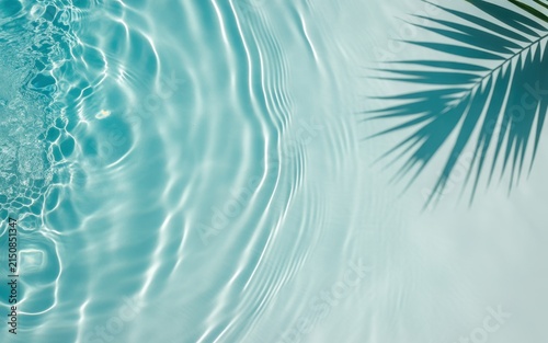 View of rippling turquoise water surface with a soft shadow of a palm leaf, creating a refreshing summer atmosphere, abstract background, light and shadow play