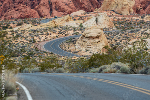 Curving scenic road crosses rugged red sandstone and desert scrub in Valley of Fire State Park, Nevada.