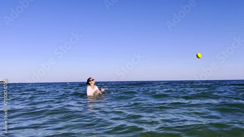 Mother and teenage son spending quality time together in the sea playing with a water ball encouraging digital detox healthy habits and emotional wellbeing. High quality FullHD footage