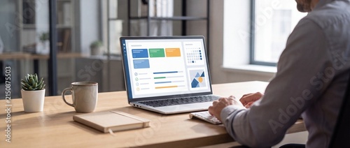 Business professional working on data analysis and project management on a laptop in a modern office setting with person working laptop with contemporary office environment