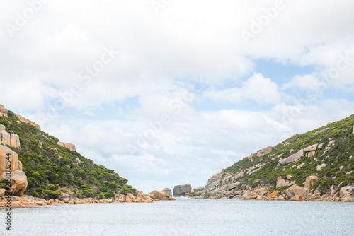 Konstfotografi Scenic view of Wychinicup Inlet showing calm water flowing between two rocky, vegetation-covered hills under a partly cloudy sky