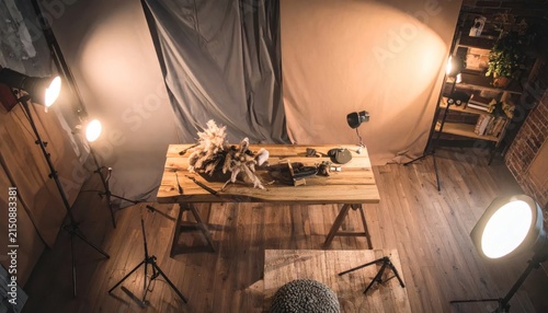Photography studio setup for product or still life shoot, featuring a wooden table with objects and studio lighting.