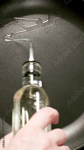 TOP VIEW: Male hand pouring oil from a bottle to a cooking pan, Slow motion