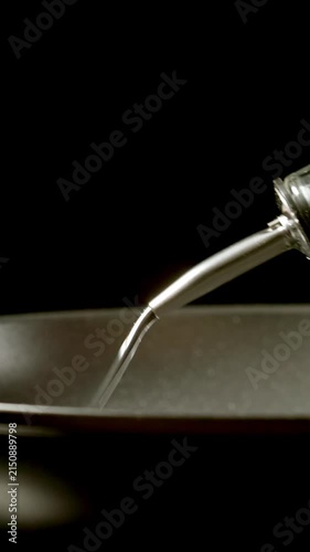 Chief hand pouring oil from a bottle to a cooking pan, Slow motion