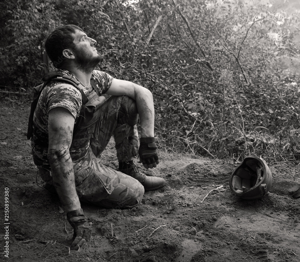 Fototapeta premium Young soldier sitting on the ground