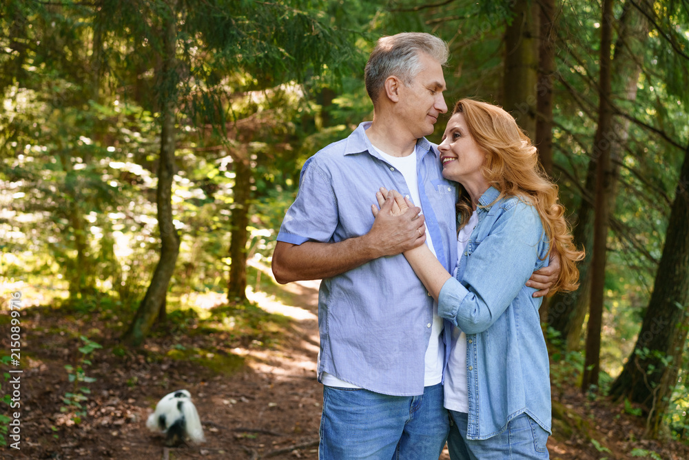 Fototapeta premium Mature Couple Embracing on a Path in a Spruce Forest
