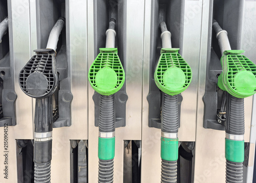 Front view of green and black fuel pump nozzles at a gas station, symbolizing rising energy prices, fuel crisis, inflation, and fossil fuel consumption.