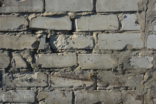 Construction and renovation work, a wall with imperfections and unevenness, the first masonry. A wall of white brick, gray cement, illuminated by the rays of the sun.