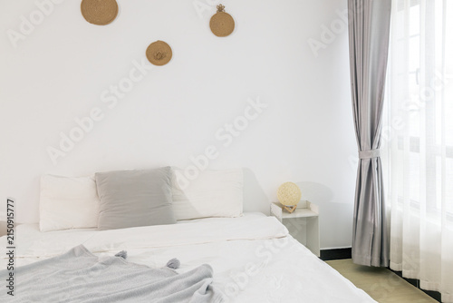 Canvastavla A minimalist bedroom with white walls, a bed with neutral pillows, and simple wall decor, featuring a small nightstand and curtains