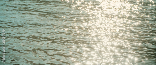Abstract water surface background with sun glare and light reflections.