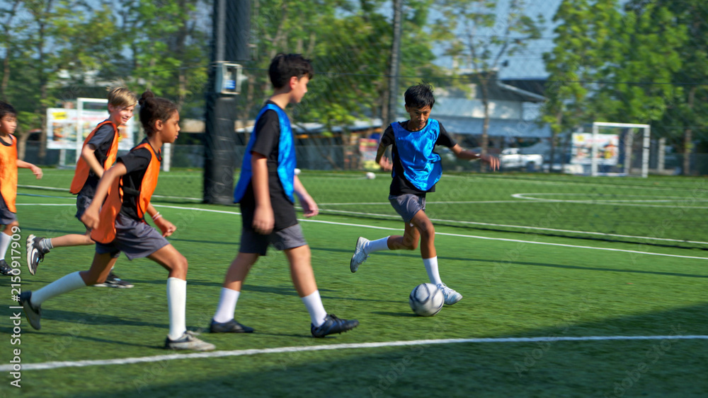 Fototapeta premium Football coach training international school students on the field,