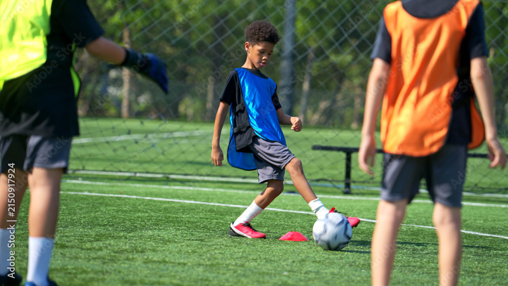 Obraz premium International school student practicing soccer dribbling on the field,