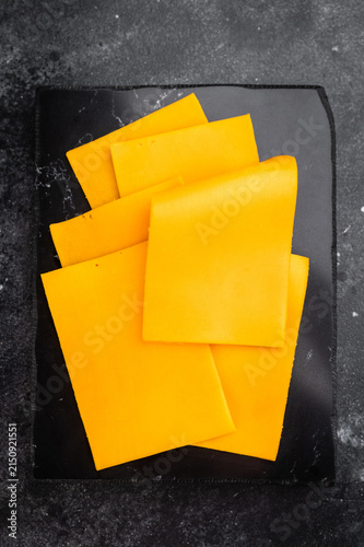 Bild auf Leinwand Stack of orange cheese slices on black stone background minimal food composition