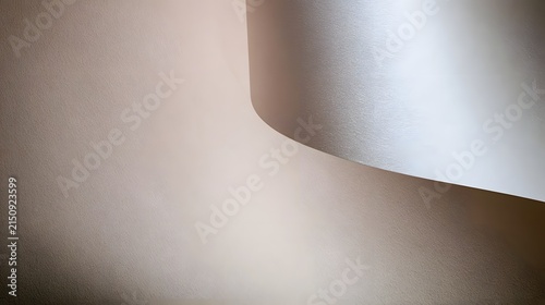 A curved metallic sheet casts soft shadows on a textured beige surface under directional lighting