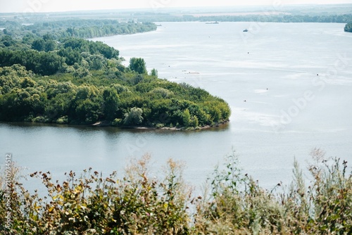 Panoramic summer landscape of the Kama River, with meadows and green trees on the bank.