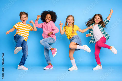 A joyful scene of four young children dancing together, smiling and having fun.