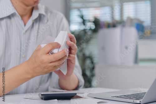 Stressed man crumpling paper receipts and bills at desk with calculator