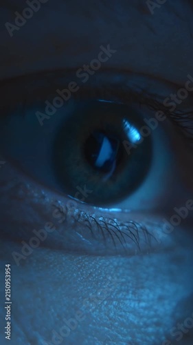 Close-up of an eye staring at a computer or smartphone screen after abruptly waking up in the dark of night. Insomnia, sleep disorder, eyestrain. Vertical video