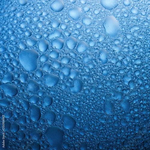 Close-up of water droplets on a glass surface with gradient blue background