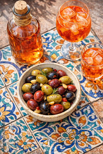 Still life of olives, wine, and cocktails on table set with colorful tiles.