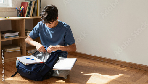 Student Organizing Backpack in Sunlit Room