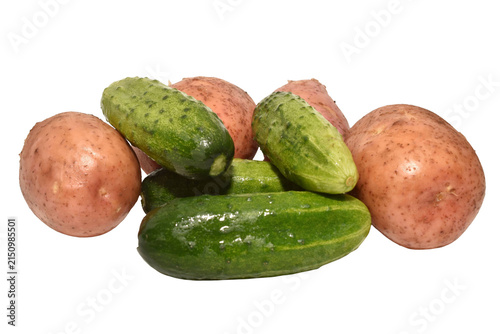 Several fresh vegetables. Ripe, pimply cucumbers and pink potato tubers lie in a pile. The cucumbers are bright green. The potatoes are large, oval-shaped tubers with pinkish skin.