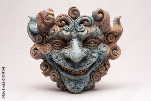 Terracotta mask with blue accents in soft studio light against a neutral backdrop representing ancient culture and folklore