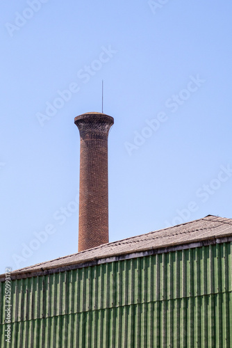 фотографія Historic Brick Industrial Chimney, Factory Roof, Green Corrugated Metal, Blue Sk