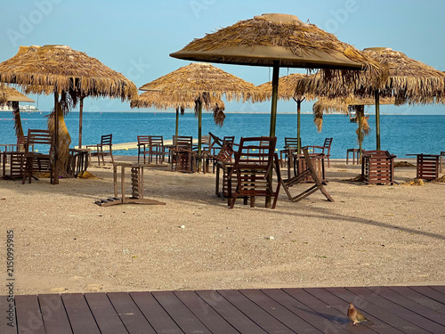 Fotografía Empty Beach with Thatched Umbrellas and Wooden Chairs on Gulf Shore