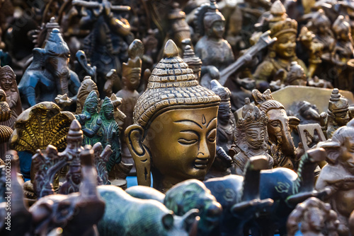 Assorted antique brass and metal Hindu god figurines, Buddha head and animal statues on display at a market in Hampi, India. Traditional religious artifacts, spiritual art objects and souvenirs.