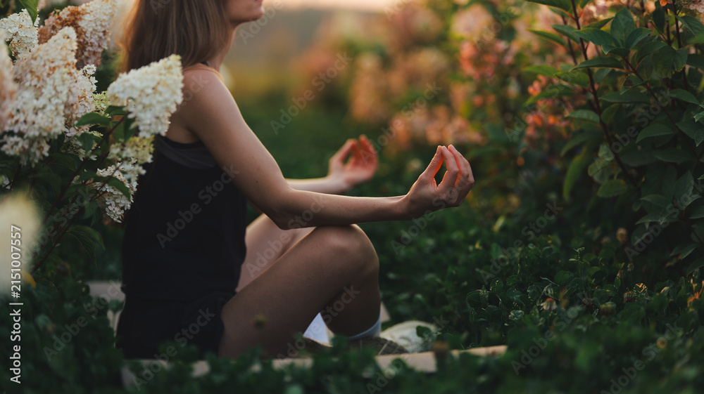 Naklejka premium Woman meditating peacefully in a lush garden at sunset
