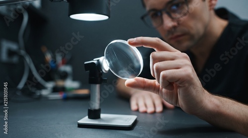 Optician inspecting lens edge under a focused task light