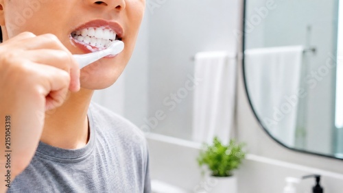 Young Adult Woman Brushing Teeth In Bathroom Near Mirror And Sink At Home