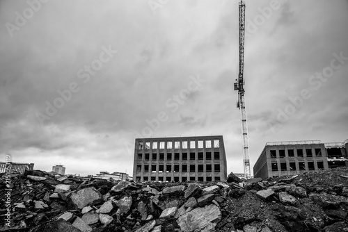 фотографія Rubble strewn foreground with tower crane and unfinished buildings beyond in bla