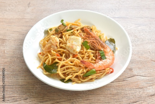 spicy stir fried spaghetti seafood slice squid and shrimp couple clam with chili and basil leaf in Thai tom yum sauce on plate