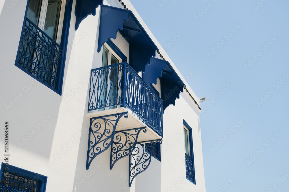 Fototapeta premium White Building with Blue Shutters and Bougainvillea in Mediterranean Town
