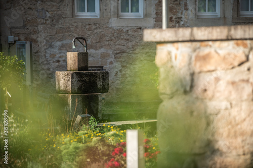 Fotografía Selektiver Fokus wegen Wassermangel leergelaufener Brunnen mit Steinquadern aus Sandstein am Kirchplatz der evangelischen Kirche St