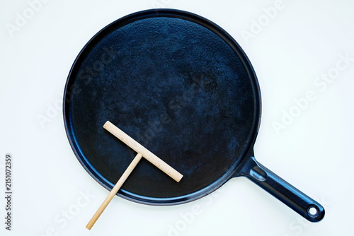 Obraz na plátne Crepe maker skillet and wooden T-shaped spreader top view on white background