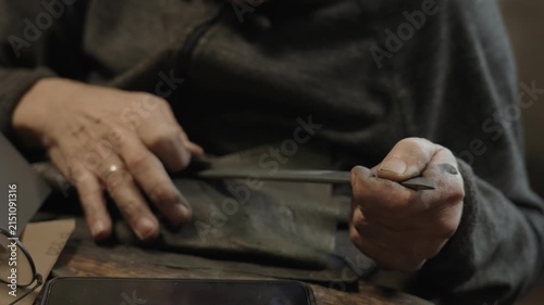 Elderly craftsman working in his old workshop, carefully restoring collectible Japanese bladed weapons