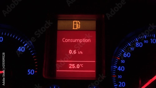 Low fuel warning light glowing on a digital car dashboard. Digital instrument cluster screen in vehicle showing fuel reserve indicator and outside temperature.